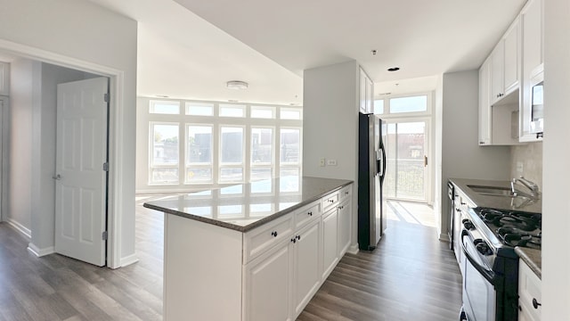 kitchen with dark stone countertops, appliances with stainless steel finishes, dark wood-type flooring, and white cabinets