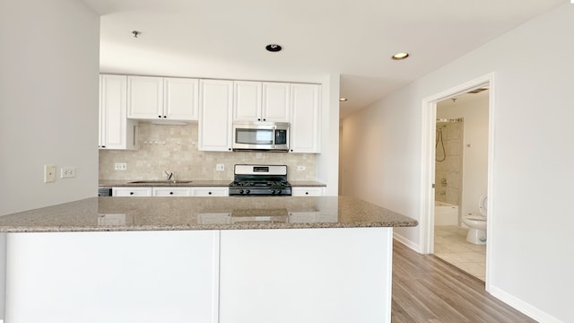 kitchen with appliances with stainless steel finishes, stone countertops, sink, and white cabinets