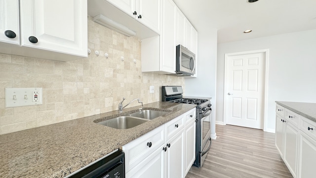 kitchen featuring sink, white cabinetry, stainless steel appliances, light stone countertops, and decorative backsplash