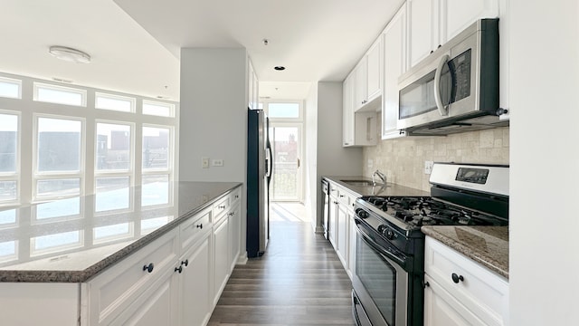 kitchen featuring stainless steel appliances, dark stone counters, and white cabinets