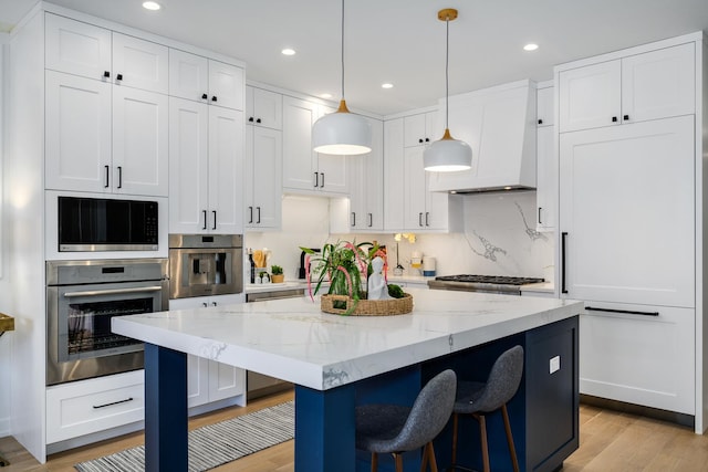 kitchen with light stone counters, decorative light fixtures, white cabinets, and appliances with stainless steel finishes