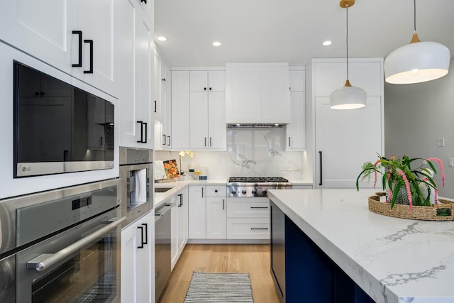 kitchen with premium range hood, white cabinetry, decorative light fixtures, stainless steel appliances, and light hardwood / wood-style floors