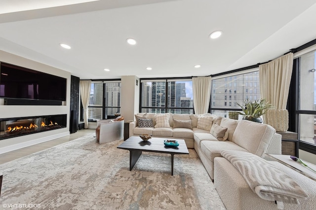 living room featuring wood finished floors, recessed lighting, a glass covered fireplace, and a city view