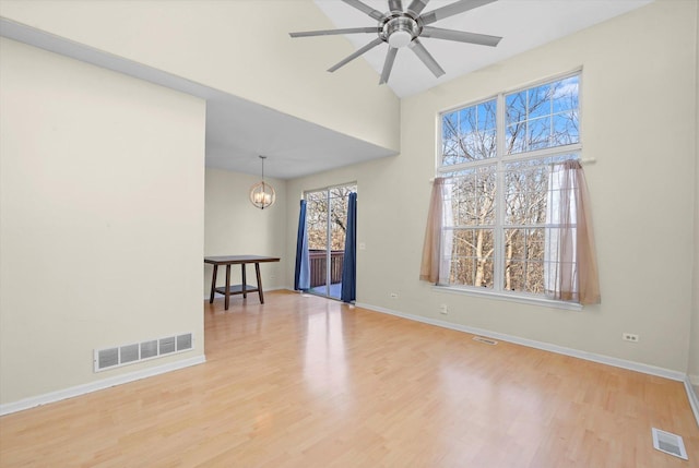 spare room featuring ceiling fan with notable chandelier and light wood-type flooring