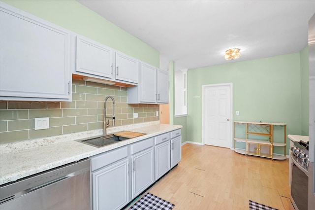 kitchen featuring sink, appliances with stainless steel finishes, light hardwood / wood-style floors, white cabinets, and decorative backsplash