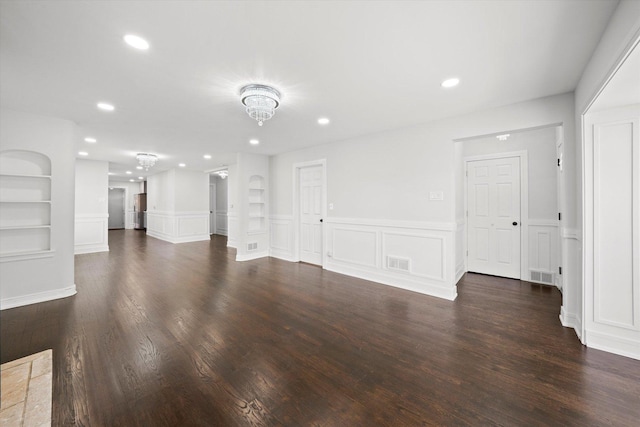 unfurnished living room with dark wood-type flooring and built in features