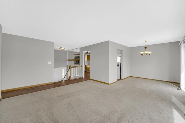 unfurnished living room with light carpet and a chandelier