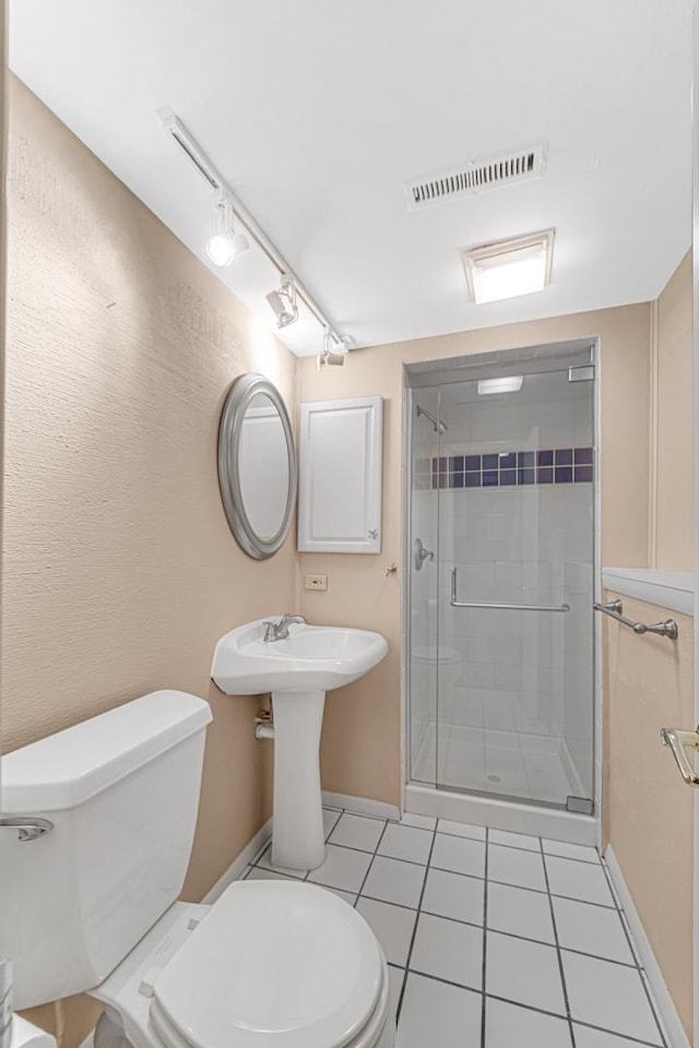 bathroom with tile patterned flooring, a shower with door, and toilet