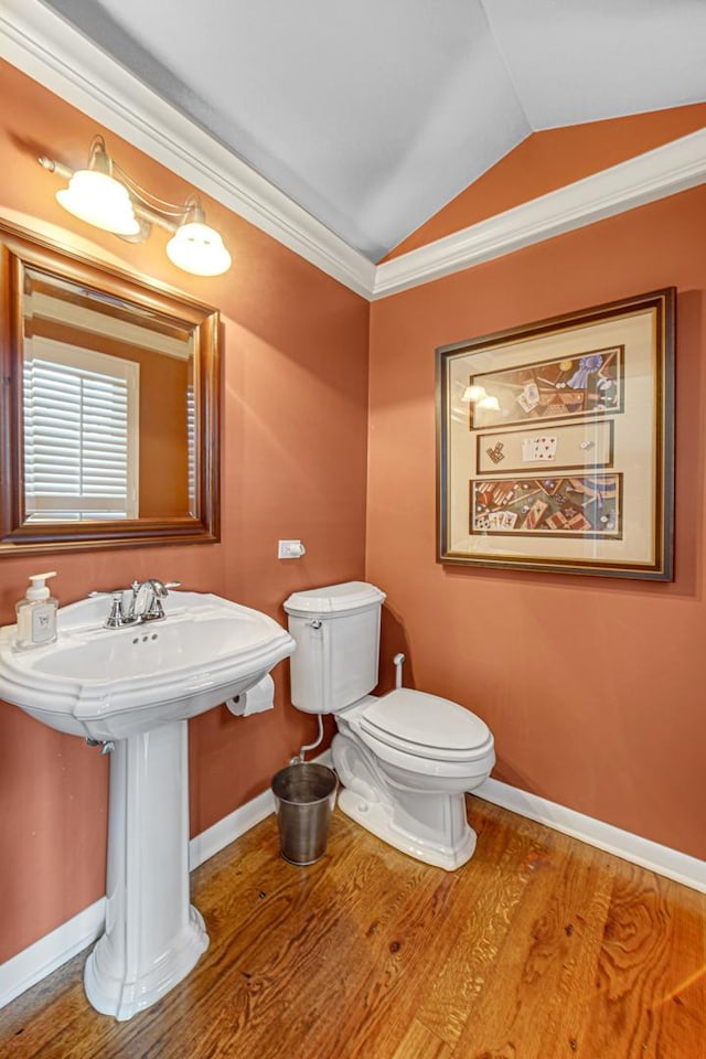 bathroom featuring hardwood / wood-style floors, lofted ceiling, sink, toilet, and crown molding