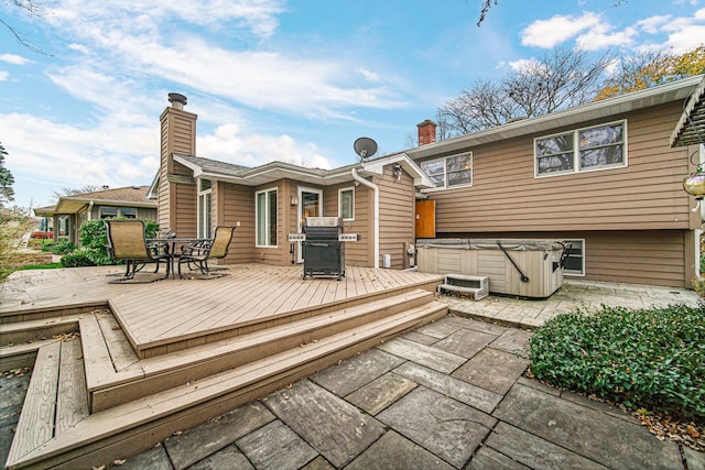 back of house with a wooden deck and a hot tub