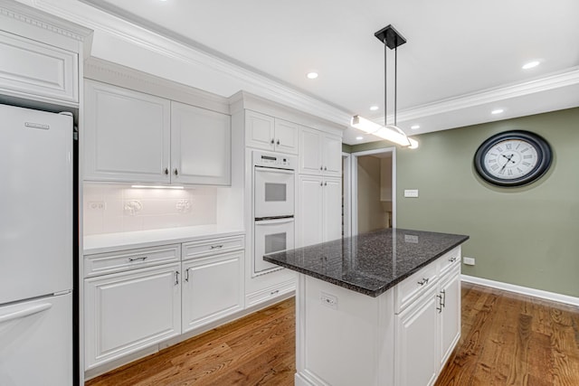 kitchen featuring white cabinetry, a center island, wood-type flooring, and white appliances