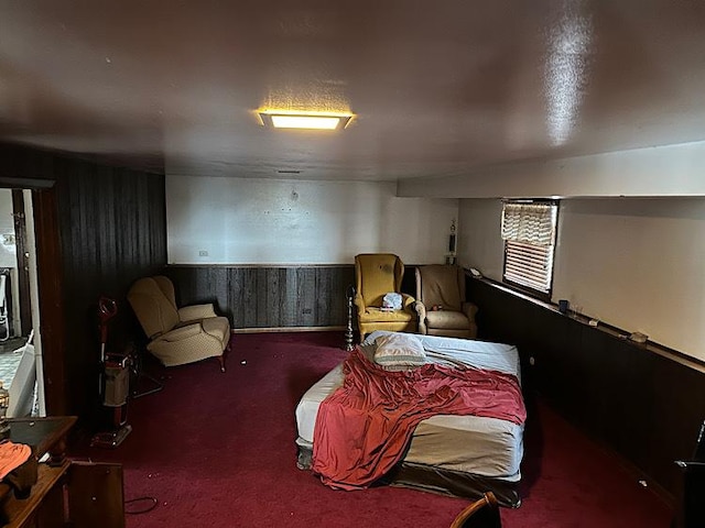 bedroom featuring wood walls, a textured ceiling, and carpet flooring