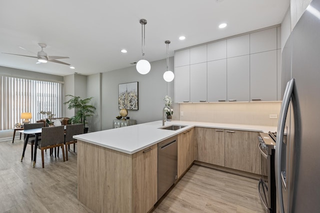 kitchen with appliances with stainless steel finishes, tasteful backsplash, sink, white cabinets, and hanging light fixtures