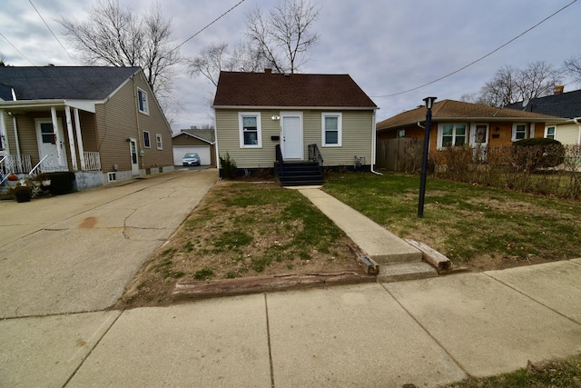 bungalow featuring a garage, an outdoor structure, and a front yard