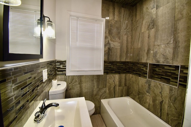 bathroom featuring a tub to relax in, toilet, sink, and tile walls