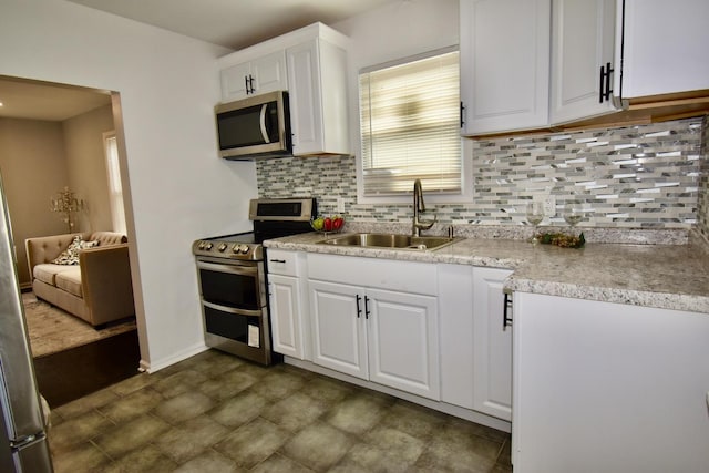 kitchen with white cabinetry, appliances with stainless steel finishes, sink, and backsplash