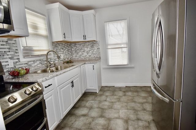 kitchen featuring stainless steel appliances, white cabinetry, sink, and decorative backsplash