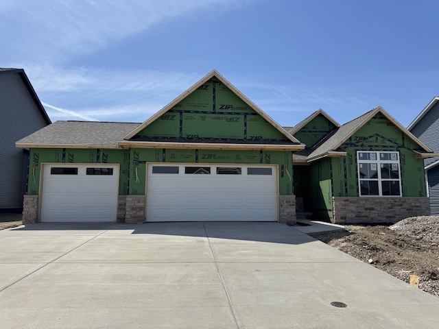 view of front facade featuring an attached garage, stone siding, and concrete driveway