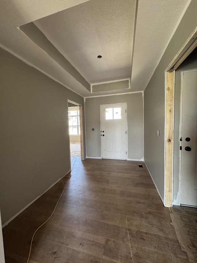 entrance foyer featuring a raised ceiling, wood finished floors, a textured ceiling, and baseboards