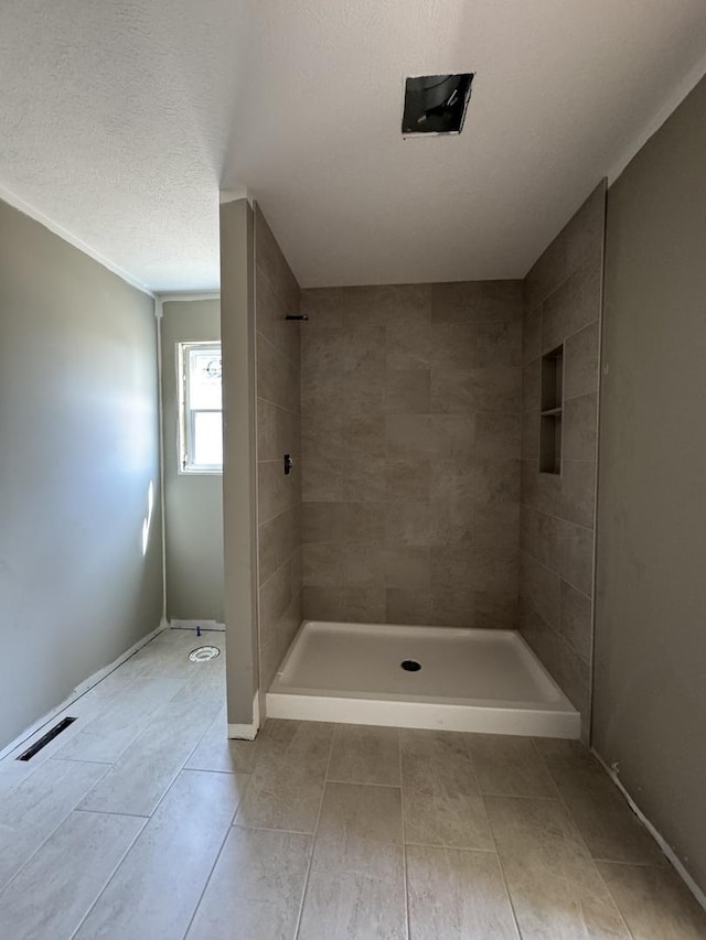 full bath featuring baseboards, visible vents, tile patterned flooring, and tiled shower