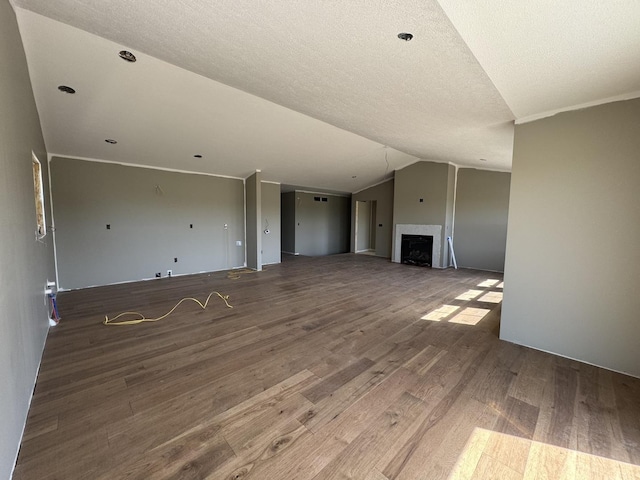 unfurnished living room with lofted ceiling, wood finished floors, a textured ceiling, and a fireplace