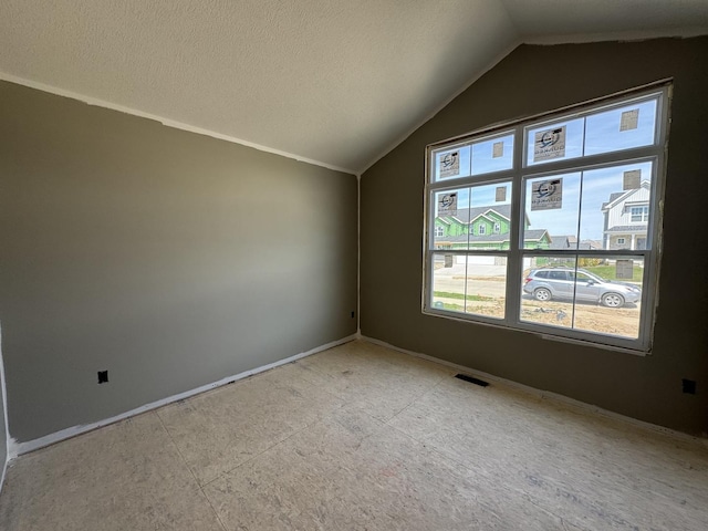 empty room with vaulted ceiling, visible vents, and baseboards