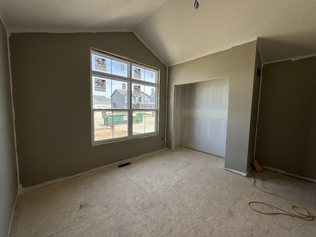 unfurnished bedroom featuring vaulted ceiling, a textured ceiling, visible vents, and a closet