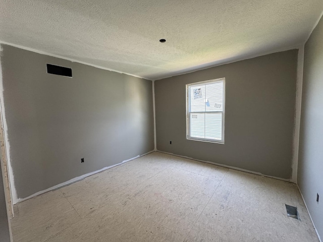 spare room with baseboards, visible vents, and a textured ceiling