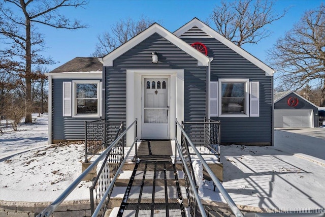 bungalow-style home with a garage and an outbuilding