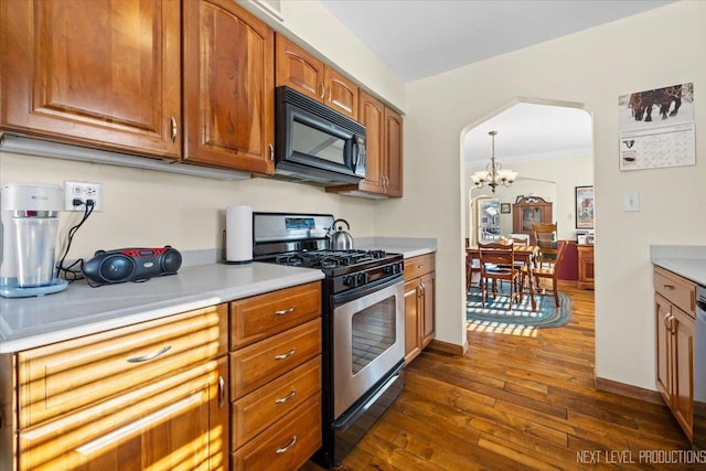 kitchen featuring arched walkways, dark wood finished floors, stainless steel gas range, light countertops, and black microwave