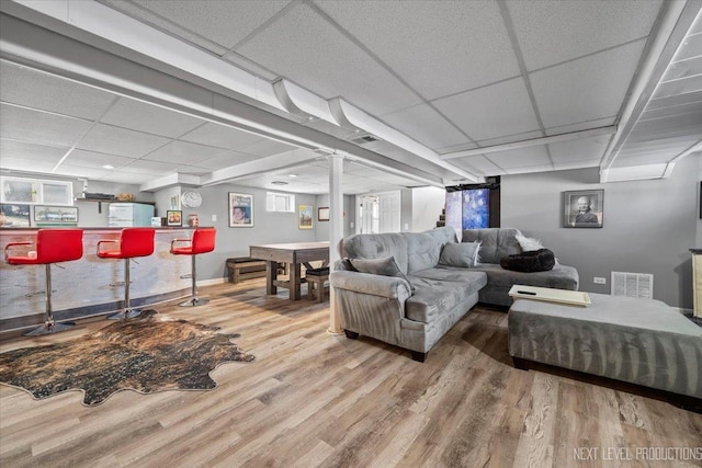 living area with visible vents, a drop ceiling, a dry bar, and wood finished floors