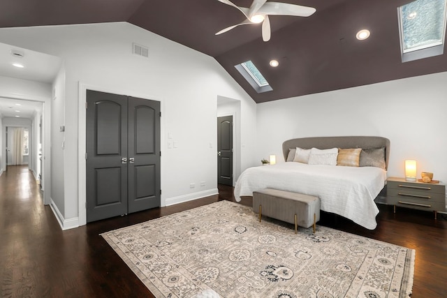 bedroom featuring ceiling fan, vaulted ceiling with skylight, a closet, and dark wood-type flooring