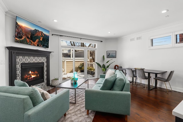 living room featuring ornamental molding, wood-type flooring, and a tiled fireplace