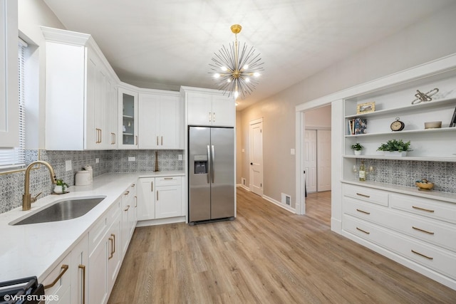 kitchen with a sink, open shelves, stainless steel fridge, light countertops, and a chandelier