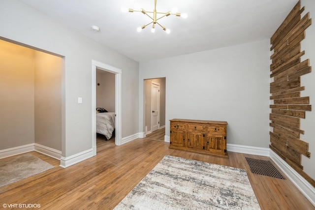 bedroom featuring visible vents, baseboards, a notable chandelier, and wood finished floors