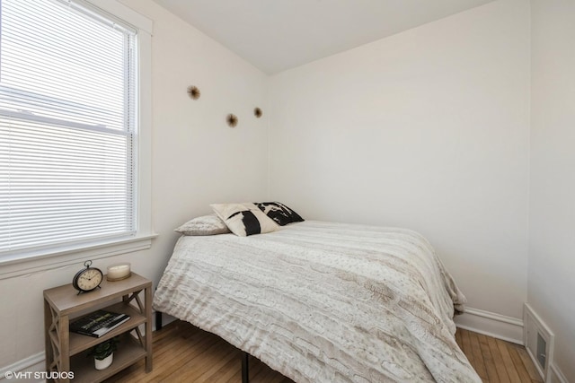 bedroom with visible vents, multiple windows, baseboards, and wood finished floors