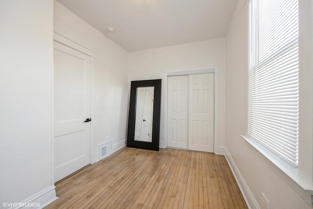 unfurnished bedroom with visible vents, baseboards, a closet, and light wood finished floors