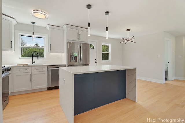 kitchen featuring stainless steel appliances, decorative backsplash, a kitchen island, and light wood-style flooring