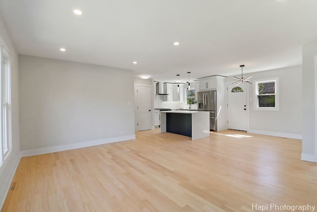 unfurnished living room with light wood-type flooring, baseboards, and recessed lighting