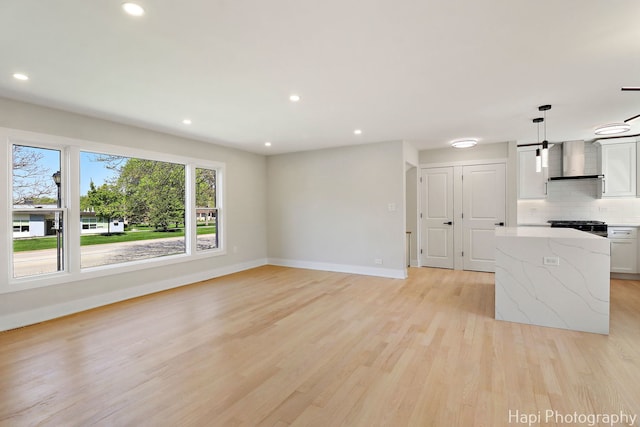 unfurnished living room featuring baseboards, light wood-type flooring, and recessed lighting