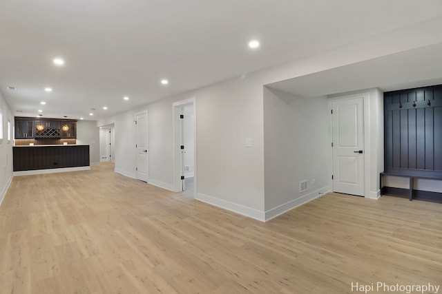 basement with light wood-type flooring, recessed lighting, baseboards, and bar