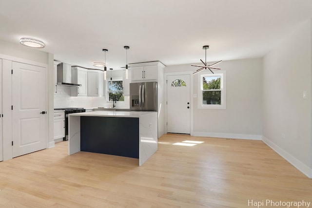 kitchen with stainless steel appliances, wall chimney exhaust hood, plenty of natural light, and a kitchen island