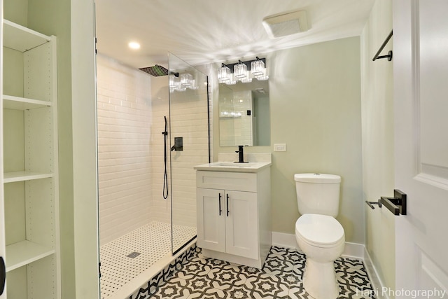 full bathroom featuring tiled shower, vanity, toilet, baseboards, and tile patterned floors