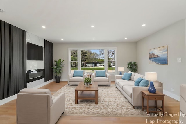living area with light wood-style flooring, recessed lighting, baseboards, and a fireplace