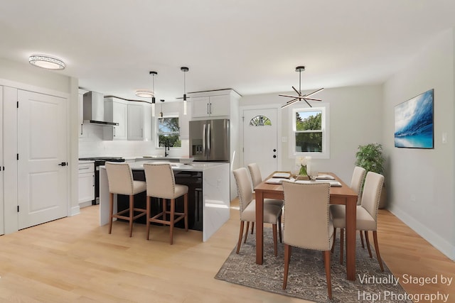 dining room featuring light wood finished floors, plenty of natural light, and baseboards
