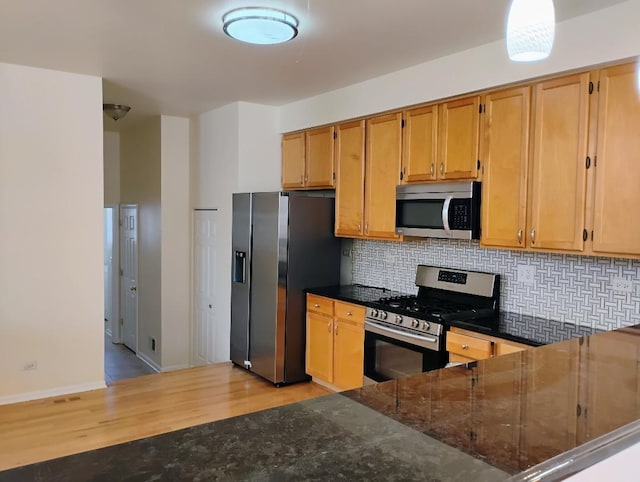 kitchen featuring decorative backsplash, light hardwood / wood-style flooring, and appliances with stainless steel finishes