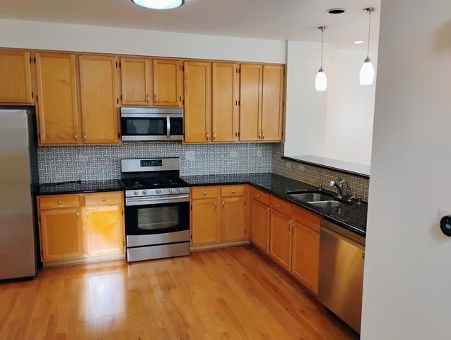 kitchen featuring pendant lighting, appliances with stainless steel finishes, sink, and light hardwood / wood-style flooring