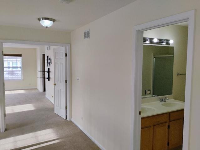 hall featuring sink and light colored carpet