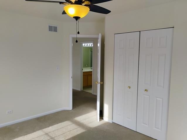 unfurnished bedroom with light colored carpet, a closet, and ceiling fan