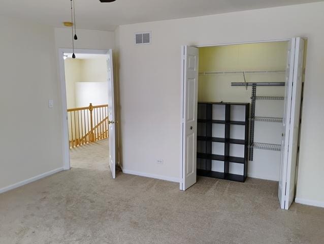 unfurnished bedroom featuring light carpet and a closet